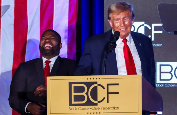 U.S. Congressman Byron Donalds chuckles while former President and Republican presidential candidate Donald Trump gives a keynote address at the Black Conservative Federation gala dinner on February 23, 2024. [Alyssa Pointer/Reuters]
