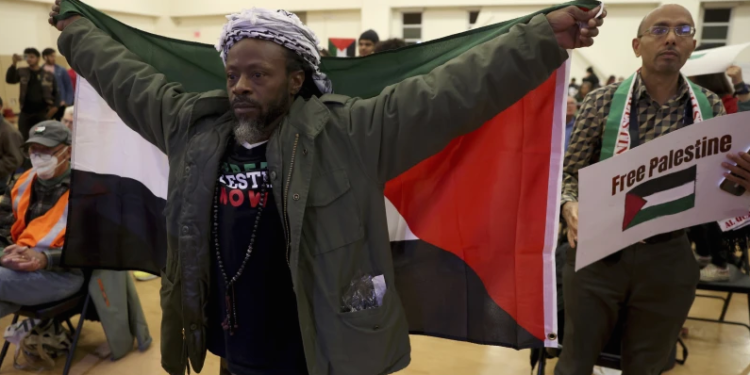 FILE - Jabari Shaw waves a Palestinian flag during an Oakland Unified School District board meeting at La Escuelita Elementary School in Oakland, California, on Wednesday, November 8, 2023. (Jane Tyska/Bay Area News Group via AP)