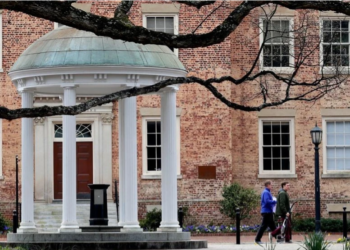 "FILE - In this file photo taken on March 18, 2020, individuals are seen removing belongings on the University of North Carolina campus in Chapel Hill, N.C. (AP Photo/Gerry Broome, File)"