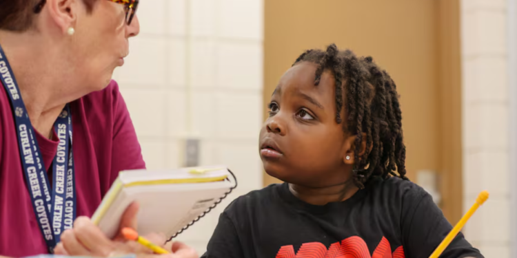 In January at Curlew Creek Elementary School, tutor Susan Cohen from the Read Across Pinellas program assists first grader Za’mir Maceachron with a reading lesson. The Pinellas County school district has launched similar initiatives aimed at closing the achievement gap among its students. [DOUGLAS R. CLIFFORD | Times]