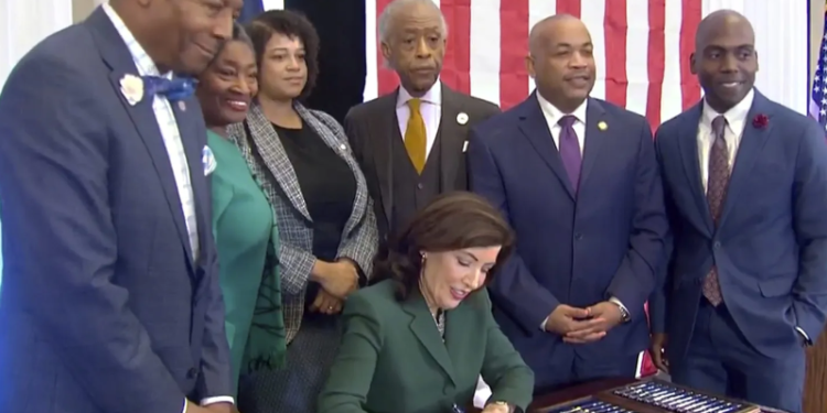 On December 19, 2023, New York Governor Kathy Hochul signed a bill establishing a commission to explore the possibility of slavery reparations. She was accompanied by Dr. Yohuru Williams of the University of St. Thomas' Racial Justice Initiative, NY State Senate Majority Leader Andrea Stewart-Cousins, Assemblywoman Michaelle Solages, Rev. Al Sharpton, NY State Assembly Speaker Carl Heastie, and State Senator James Sanders.