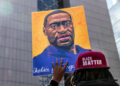 Protesters display signs in tribute to George Floyd during a demonstration outside the Hennepin County Government Center on March 28, 2021, in Minneapolis, Minnesota.