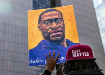 Protesters display signs in tribute to George Floyd during a demonstration outside the Hennepin County Government Center on March 28, 2021, in Minneapolis, Minnesota.