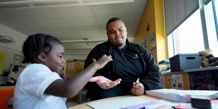 "On Thursday, Oct. 3, 2024, at Dorothy I. Height Elementary School in Baltimore, Leading Men fellow Davontez Johnson shares a high-five with preschooler Kodi during a name-writing activity. (AP Photo/Stephanie Scarbrough) The Associated Press"