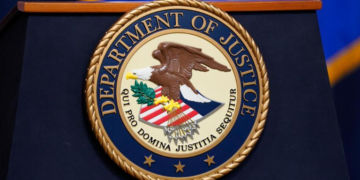 The United States Department of Justice seal is shown on a podium ahead of a news conference at the Justice Department in Washington, on Thursday, April 13, 2023. (AP Photo/Evan Vucci, File)