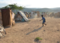 A boy plays with an abandoned tire at a border encampment near the southeastern Haitian town of Anse-à-Pitres. (Photo: Dave McFadden/AP)