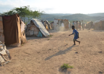 A boy plays with an abandoned tire at a border encampment near the southeastern Haitian town of Anse-à-Pitres. (Photo: Dave McFadden/AP)