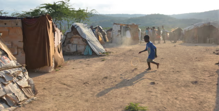 A boy plays with an abandoned tire at a border encampment near the southeastern Haitian town of Anse-à-Pitres. (Photo: Dave McFadden/AP)