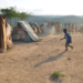 A boy plays with an abandoned tire at a border encampment near the southeastern Haitian town of Anse-à-Pitres. (Photo: Dave McFadden/AP)