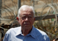Former U.S. President Jimmy Carter is pictured standing before the contentious Israeli barrier during his visit to the West Bank village of Bilin near Ramallah on August 27, 2009. REUTERS/Ammar Awad/File Photo. Purchase Licensing Rights.