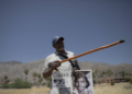 On May 30, 2024, Wendell Crawford holds up a poster featuring images of his family, who once lived in Palm Springs' Section 14 neighborhood. Pointing to the spot where his family’s home once stood, he recalled, "I used to walk through these grounds." (Zaydee Sanchez/KQED)