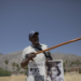 On May 30, 2024, Wendell Crawford holds up a poster featuring images of his family, who once lived in Palm Springs' Section 14 neighborhood. Pointing to the spot where his family’s home once stood, he recalled, "I used to walk through these grounds." (Zaydee Sanchez/KQED)