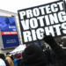 In 2022, a participant in Washington, D.C.'s annual Martin Luther King Jr. Memorial Peace Walk held a sign reading "PROTECT VOTING RIGHTS." Photo by Mandel Ngan/AFP via Getty Images.