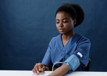 a healthcare worker measuring her own blood pressure using a sphygmomanometer