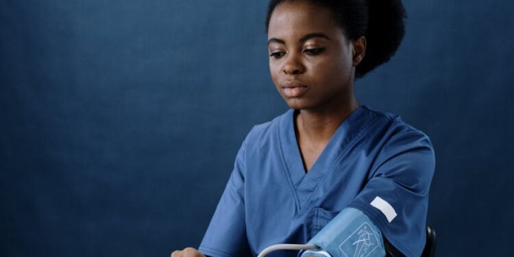a healthcare worker measuring her own blood pressure using a sphygmomanometer