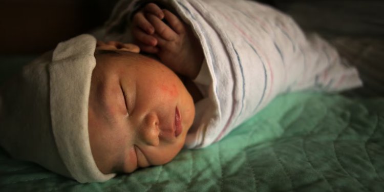 A newborn rests alongside his mother at the Lawrence General Hospital Birthing Center in 2022. (Lane Turner/Globe Staff)