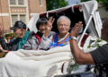 Survivors of the Tulsa Race Massacre, from left to right, Hughes Van Ellis Sr., Lessie Benningfield Randle, and Viola Fletcher, wave and high-five supporters from a horse-drawn carriage ahead of a march in Tulsa, Oklahoma, on May 28, 2021. (Photo by Sue Ogrocki / AP Photo)