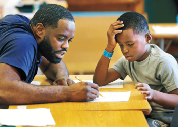 Eight-year-old Marquise Mayes completes his math homework with the help of his teacher at Lloyd Barbee Montessori School in Milwaukee, Wisconsin.