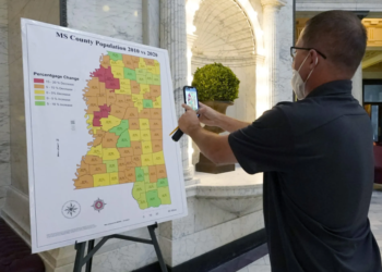 A visitor at the Mississippi Capitol in Jackson captures a photo on his cell phone of a graphic illustrating the census growth or decline across the state's counties over a 10-year span, on Thursday, Aug. 26, 2021. (AP Photo/Rogelio V. Solis)