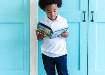 a cute boy standing while reading a book
