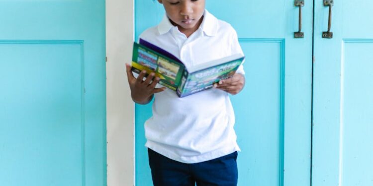 a cute boy standing while reading a book