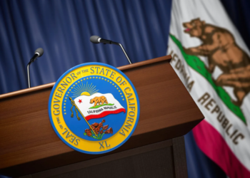 Governor of California Press Conference Concept: A 3D illustration depicting the Seal of the Governor of the State of California displayed on a podium, accompanied by the flags of the United States and the State of California in the background.