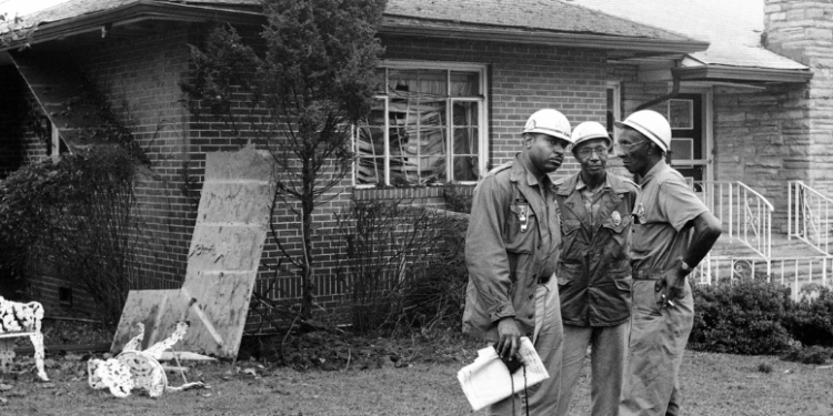 Three civil rights activists stand watch outside NAACP attorney Arthur Shores' home in September 1963, a day after it was struck by a dynamite explosion. — AP
