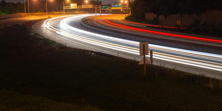 time lapse photography of fast moving cars on the road during night time