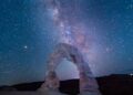 arched rock formation under starry sky