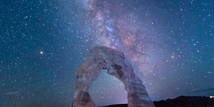 arched rock formation under starry sky