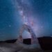 arched rock formation under starry sky