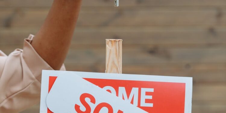 a sold signboard and a person holding keys