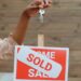 a sold signboard and a person holding keys