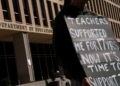 A demonstrator stands outside the Department of Education headquarters in Washington, D.C., on March 12, following the agency’s announcement of plans to lay off nearly half its workforce. The move, which some fear could signal an eventual shutdown, comes as government agencies rush to meet President Donald Trump’s deadline for submitting proposals for a second wave of mass layoffs. (Nathan Howard/Reuters)
