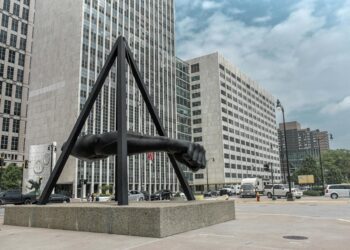 statue of human arm near gray buildings