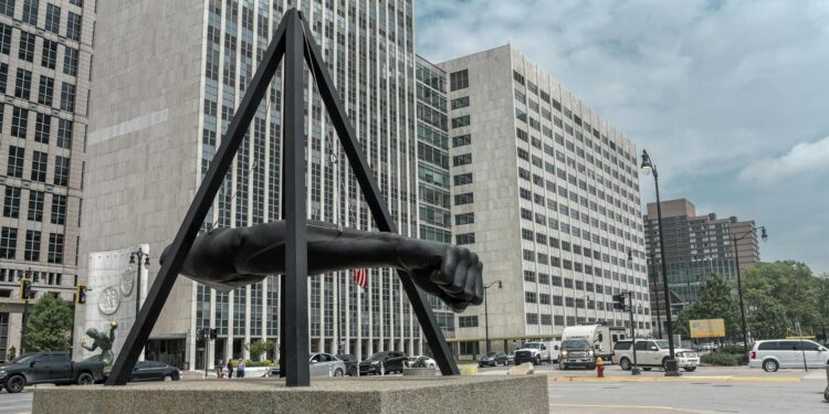 statue of human arm near gray buildings