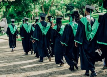 university graduates walking in outdoor ceremony