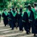 university graduates walking in outdoor ceremony