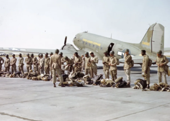 "In 1945, paratroopers of the 555th Parachute Infantry Battalion lined up in their 'jumpsuits' before embarking on a mission. Behind them stands a C-47 aircraft from the Troop Carrier Command, ready to transport them to their destination."— US National Archives